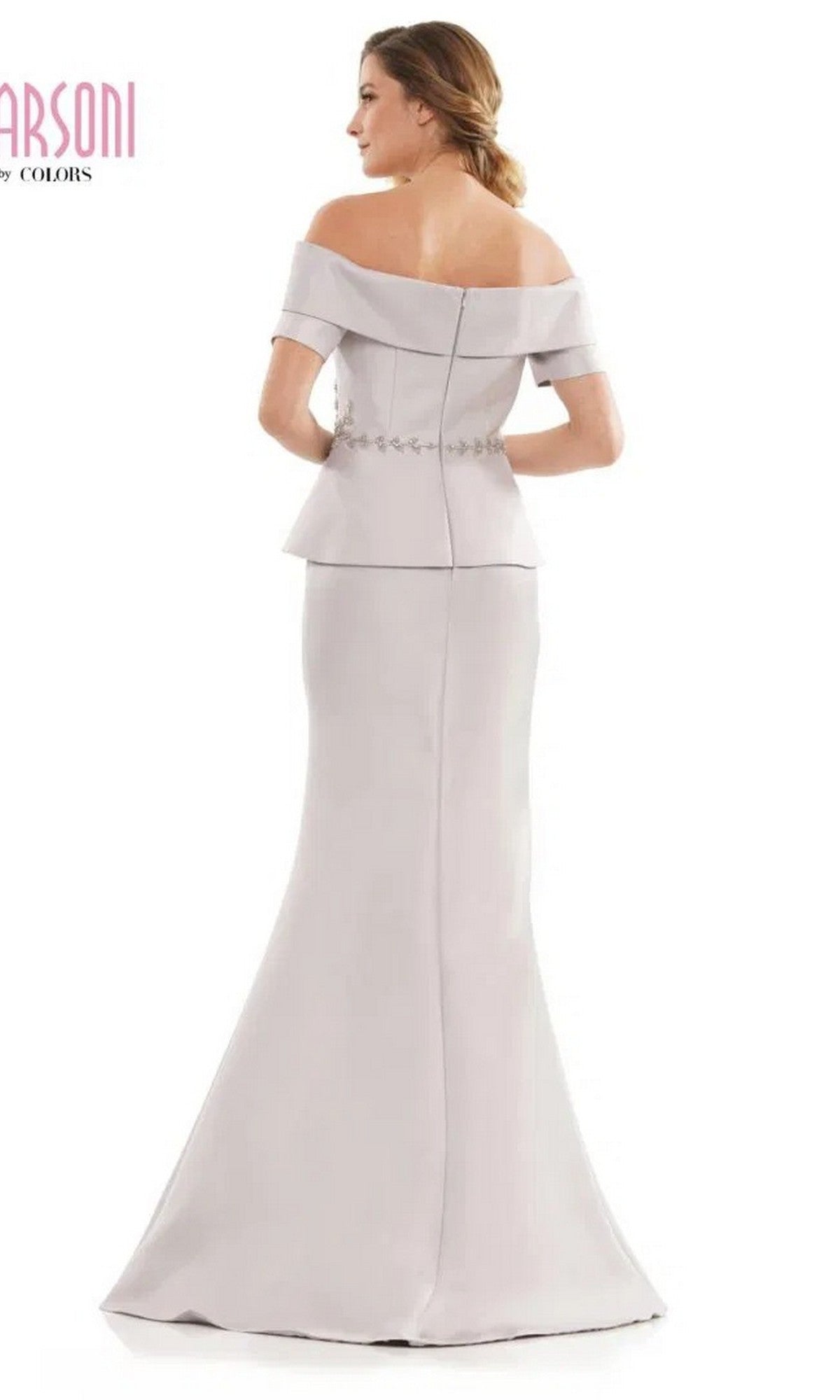 A woman faces away from the camera, wearing the Marsoni MV1144 long formal dress, which features an off-the-shoulder neckline, beaded peplum waistline, and decorative buttons down the back.